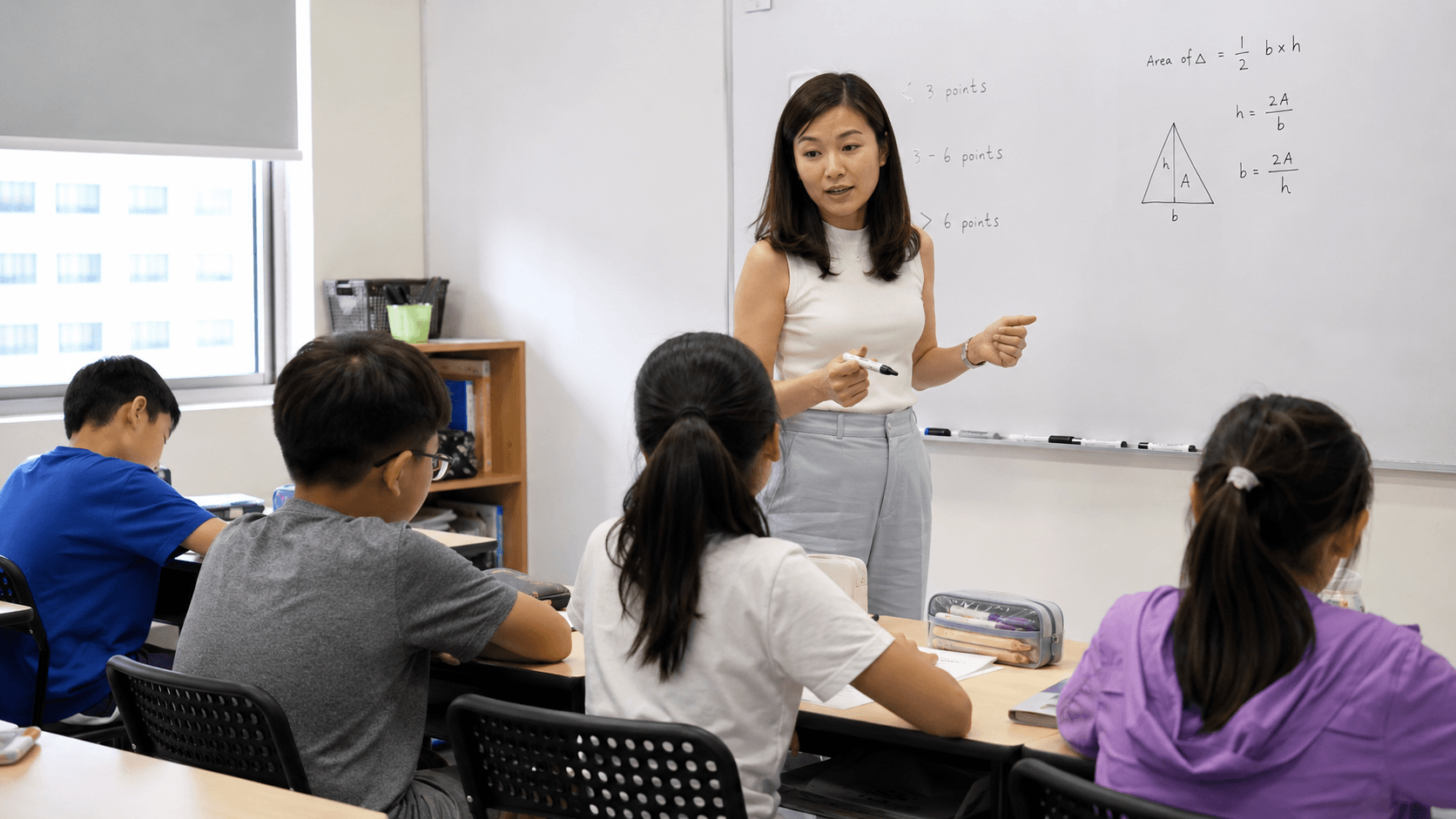 Small classroom, students at desks, teacher with worksheets